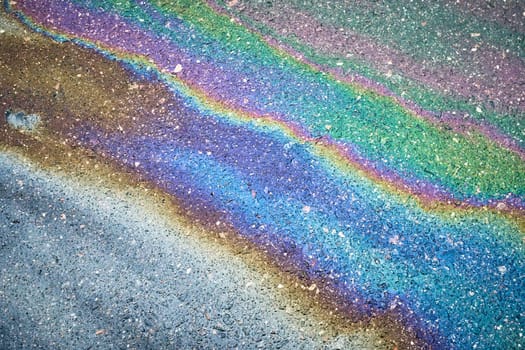 Colorful oil slick reflecting a spectrum of hues on the wet pavement