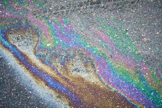 Rainbow-hued oil spill creating an enchanting sheen on the wet asphalt surface