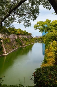 OSAKA, JAPAN - SEPTEMBER 25 2024: The iconic Osaka Castle and surrounding moat and gardens on a warm clear autumn day in Osaka, Japan on September 25th 2024