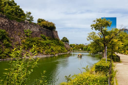 OSAKA, JAPAN - SEPTEMBER 25 2024: The iconic Osaka Castle and surrounding moat and gardens on a warm clear autumn day in Osaka, Japan on September 25th 2024