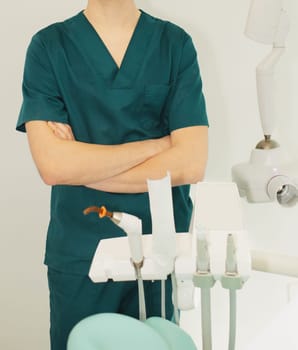 Dentist man in office near chair with dental tools