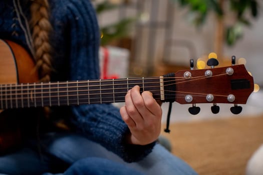 A skilled hand skillfully strumming the strings of an acoustic guitar, creating music in a warm, inviting atmosphere