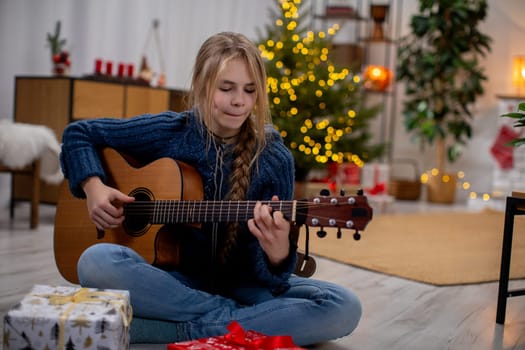 A joyful girl plays guitar among festive decorations and gifts, capturing the spirit of the holidays.