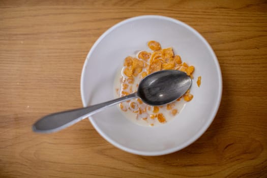 This image offers a closeup view of a vibrant bowl filled with colorful cereal alongside a spoon on a wooden surface
