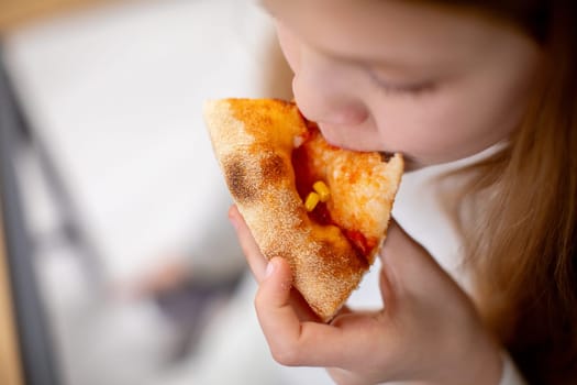 A young child takes a huge and delicious bite of cheesy pizza, capturing a blissful moment of joy and indulgence