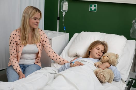 A loving mother provides comfort and emotional support for her sick daughter in a hospital room, fostering care