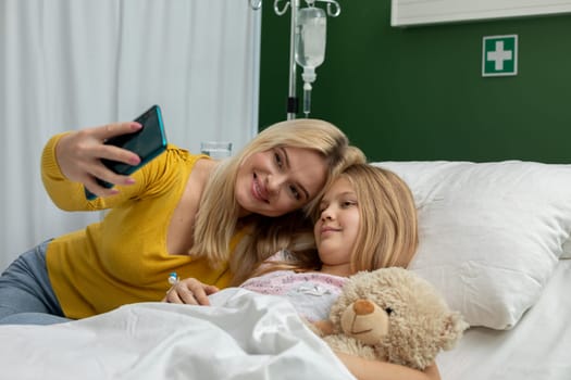 A heartwarming and touching moment captured as a mother and daughter share a selfie in a cozy hospital room