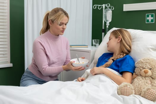 A devoted and caring mother provides tender comfort and unwavering assistance to her daughter in a hospital bed