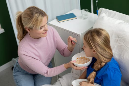 In a nurturing hospital, a compassionate caregiver feeds a young girl, showcasing care and affection