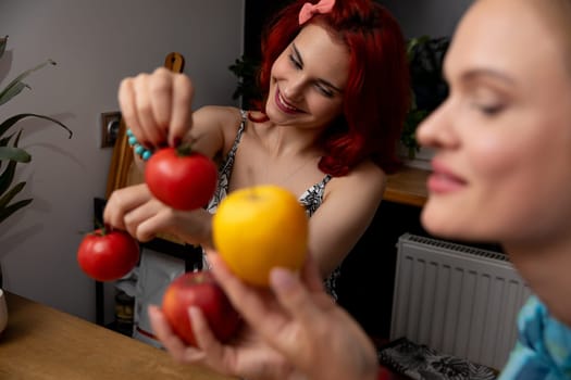 Two women are joyfully and enthusiastically selecting vibrant and colorful tomatoes in a cozy kitchen setting