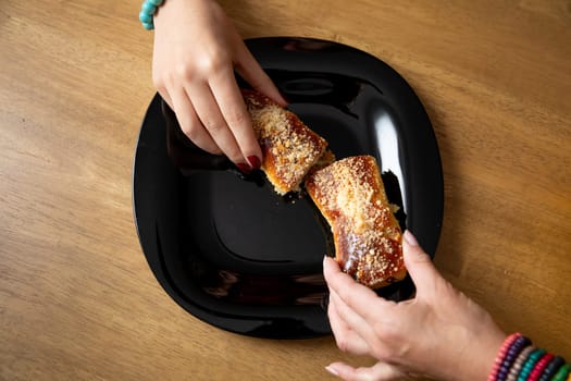Two eager hands are reaching for a flaky pastry, beautifully highlighting the pure joy of sharing delicious food
