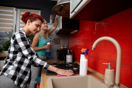A group of friends are happily enjoying cooking together in a modern kitchen that is filled with vibrant colors