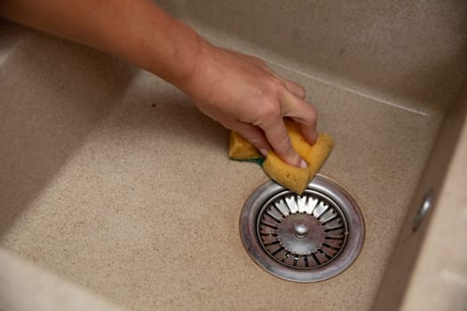 A person vigorously cleaning a kitchen sink with a sponge, promoting hygiene and overall cleanliness