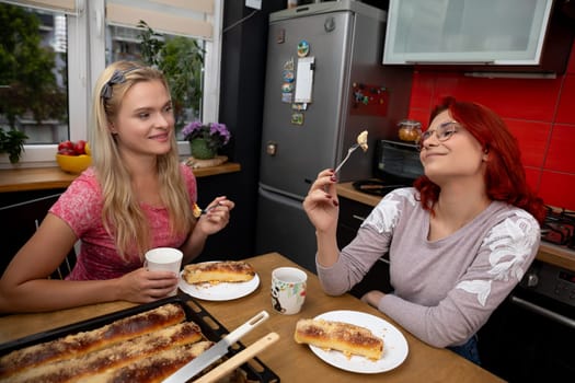 Two close friends share a delightful moment enjoying delicious and tasty food in a cozy, warm kitchen setting