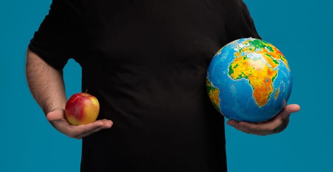 A person holds an apple in one hand and a globe in the other, illustrating the contrast between a singular object and the vastness of the Earth, emphasizing perspective and scale in a playful manner.