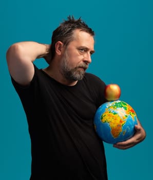 A thoughtful man stands against a bright blue backdrop, holding a globe in one arm while a red apple balances on top. His gaze is contemplative, suggesting a deep connection to the world and nature.