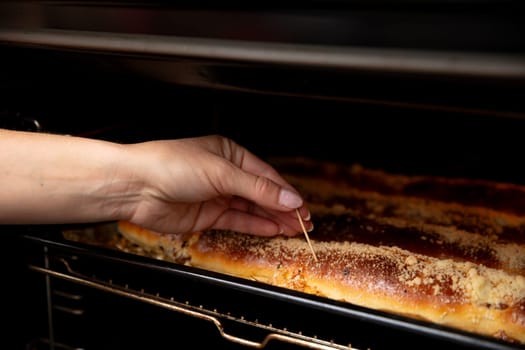 A hand is carefully testing freshly baked bread inside the oven to ensure it achieves perfect doneness and flavor