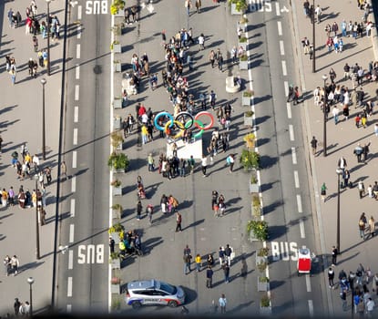 A lively crowd gathers around the Olympic rings in a busy urban area, showcasing excitement and community spirit. Paris, France - October 24, 2024