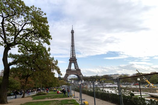Experience a breathtaking view of the iconic Eiffel Tower perfectly framed by vibrant, colorful trees and a cloudy sky. Paris, France - October 24, 2024