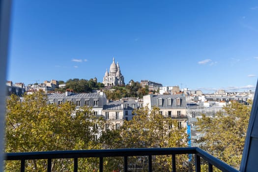 Stunning skyline view featuring Sacr Cur Basilica amidst blue skies and rooftops. Paris, France - October 26