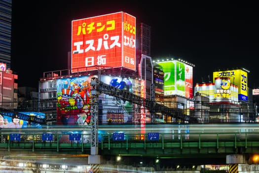 TOKYO, JAPAN, SEPTEMBER 16 2024: Train and traffic in Tokyo’s busy Shinjuku neighborhood at night in Japan