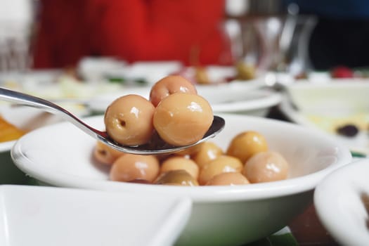 Closeup of beautiful olives in a bowl with a spoon, ideal for appetizers and sharing