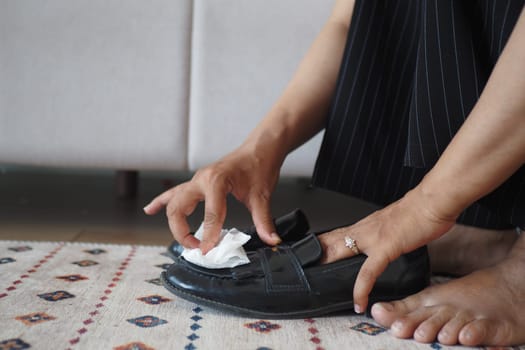A person is polishing black shoes with a cloth to ensure they look neat and tidy