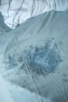 A visible stain on a light blue bedsheet,