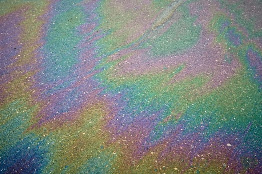 Colorful gasoline or diesel fuel spill on asphalt creating a rainbow effect after the rain