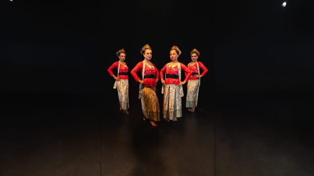 a group of female dancers in red costumes standing in a harmonious and equal position on the stage at night