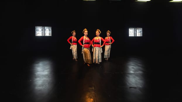 a group of female dancers in red costumes standing in a harmonious and equal position on the stage at night