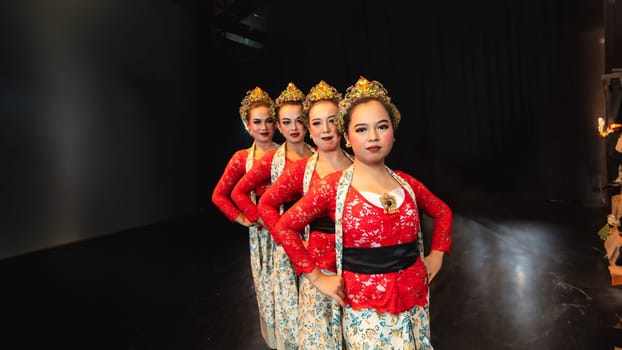 a group of female dancers in red costumes standing in a harmonious and equal position on the stage at night