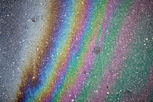 Gasoline rainbow colors creating an oil slick on asphalt road