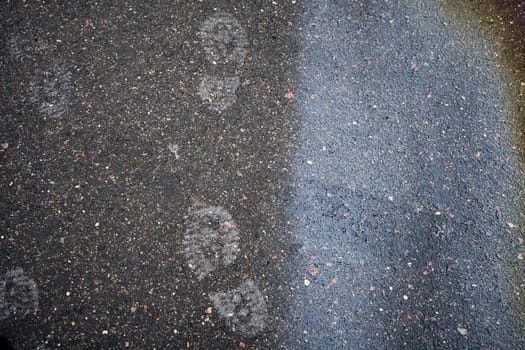 Rainbow oil spill reflecting on wet asphalt with footprint