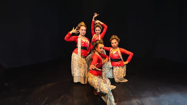 a group of traditional Indonesian dancers look elegant and beautiful when wearing red costumes in front of the audience at night