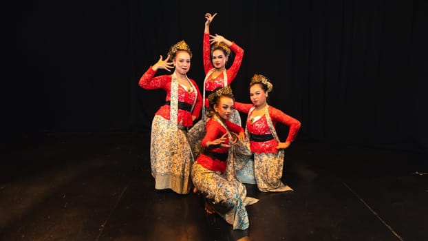 A group of traditional Sundanese dancers radiate elegant charm to the audience with their movements and red costumes on stage at night