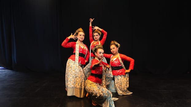 A group of traditional Sundanese dancers radiate elegant charm to the audience with their movements and red costumes on stage at night