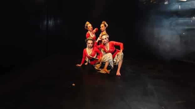 a group of traditional Javanese dancers wearing red costumes which provide a dramatic effect on the stage at night