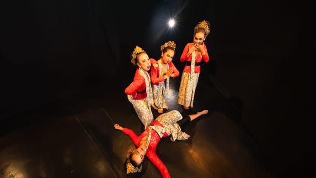 a group of traditional Javanese dancers wearing red costumes which provide a dramatic effect on the stage at night