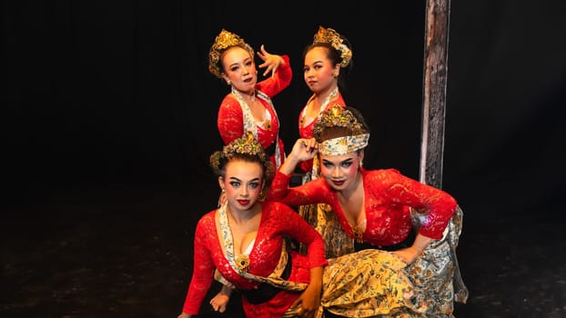 a group of traditional Javanese dancers wearing red costumes which provide a dramatic effect on the stage at night