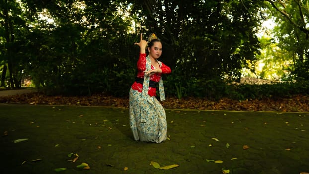 a Javanese dancer wearing a red costume that is thick with legends and religious rituals while in the forest in the afternoon