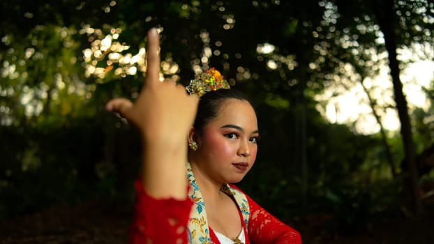 a Javanese dancer wearing a red costume that is thick with legends and religious rituals while in the forest in the afternoon