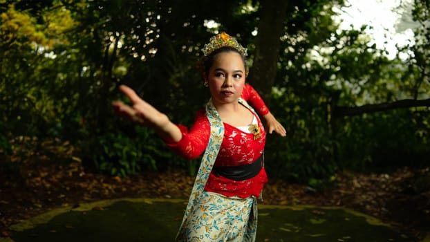 a Javanese dancer wearing a red costume that is thick with legends and religious rituals while in the forest in the afternoon