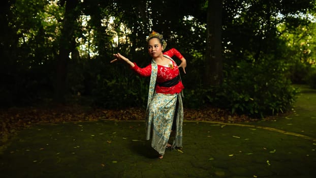 a Javanese dancer wearing a red costume that is thick with legends and religious rituals while in the forest in the afternoon