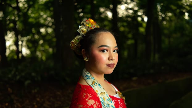 a traditional Sundanese dancer wearing a red costume which is the identity of a stunning and impressive dancer when in the forest in the afternoon