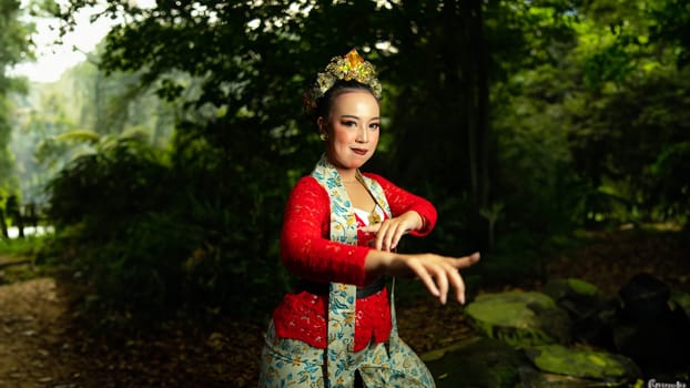 a traditional Sundanese dancer wearing a red costume which is the identity of a stunning and impressive dancer when in the forest in the afternoon