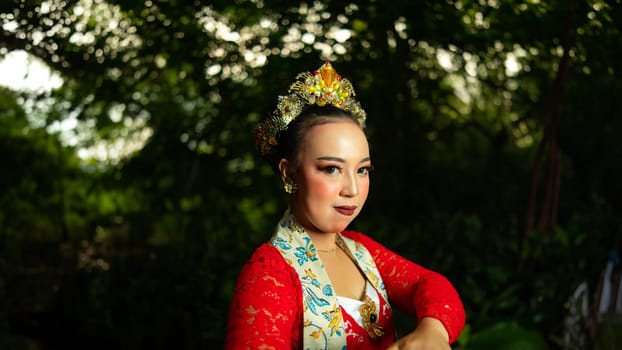 a traditional Sundanese dancer wearing a red costume which is the identity of a stunning and impressive dancer when in the forest in the afternoon