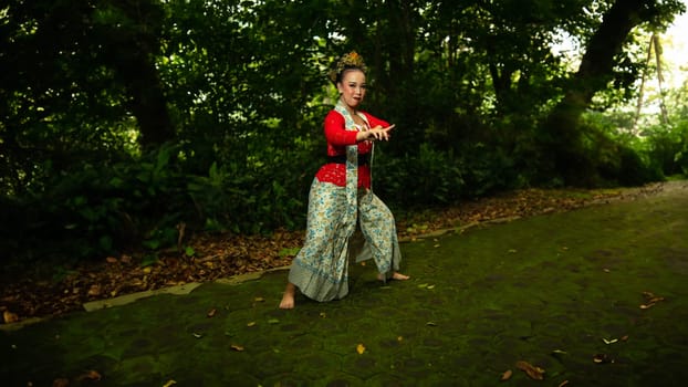 a traditional Sundanese dancer wearing a red costume which is the identity of a stunning and impressive dancer when in the forest in the afternoon