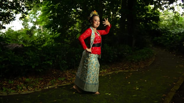 a traditional Sundanese dancer wearing a red costume which is the identity of a stunning and impressive dancer when in the forest in the afternoon