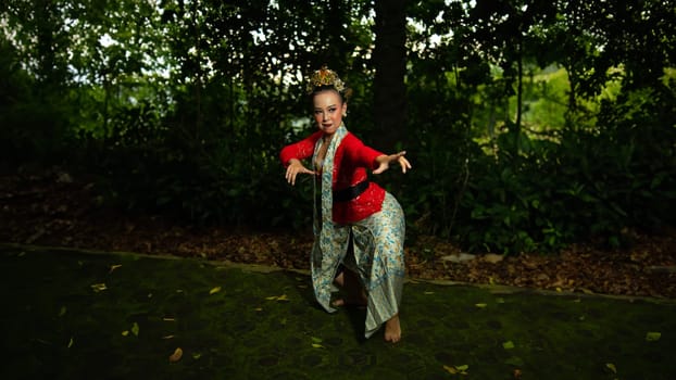 a traditional Indonesian dancer performs in a traditional ceremony and cultural festival in the forest in the morning